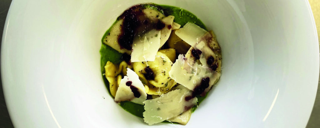 Cappelletti con salsa verde, scaglie di parmigiano, funghi e gocce di aglio nero.