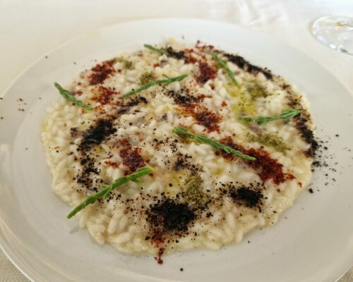 Risotto camouflage alle vongole con polvere di aglio nero, peperone crusco e salicornia croccante.